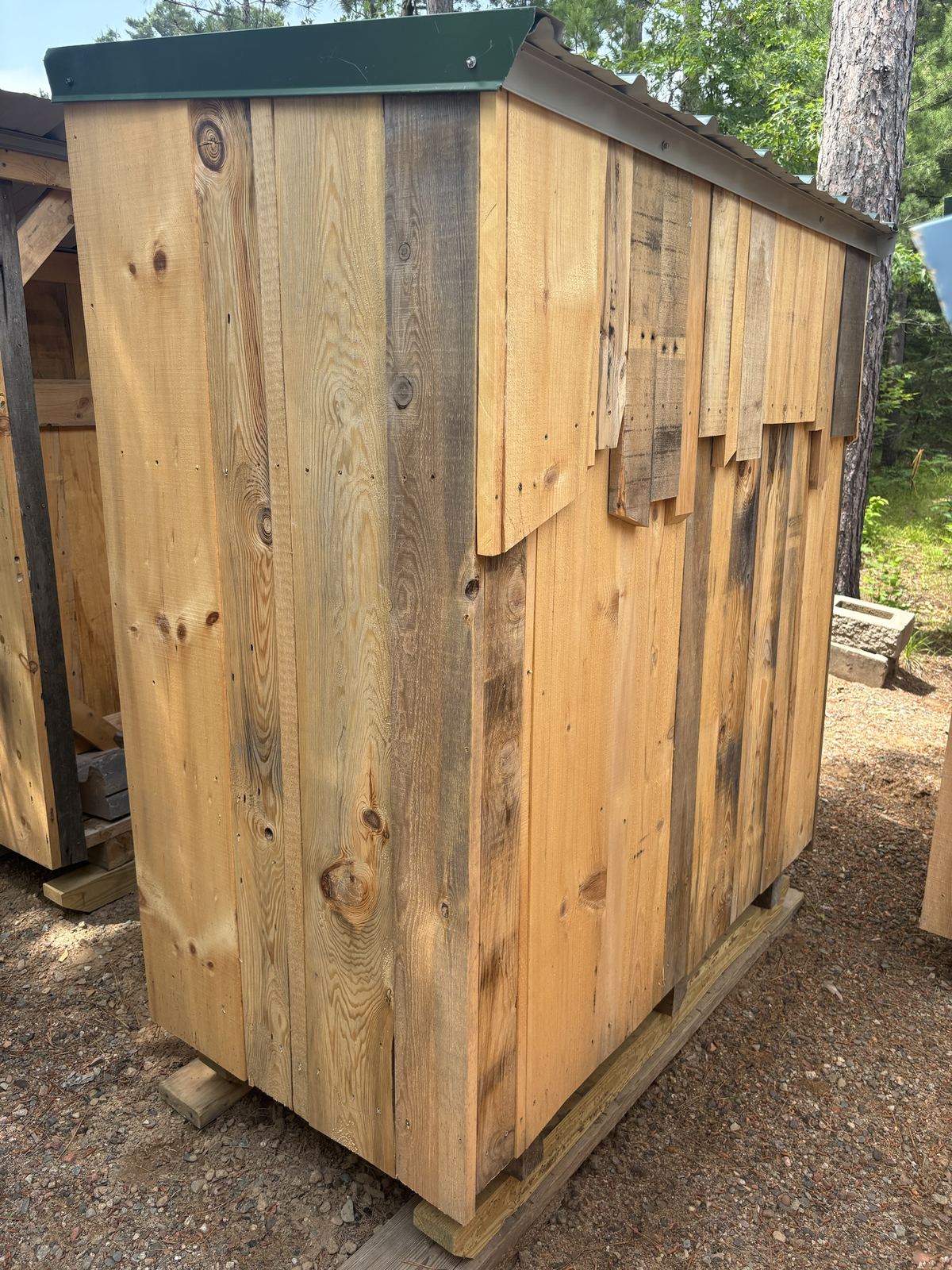Back of a shed with a jagged row of salvaged-look boards across the top