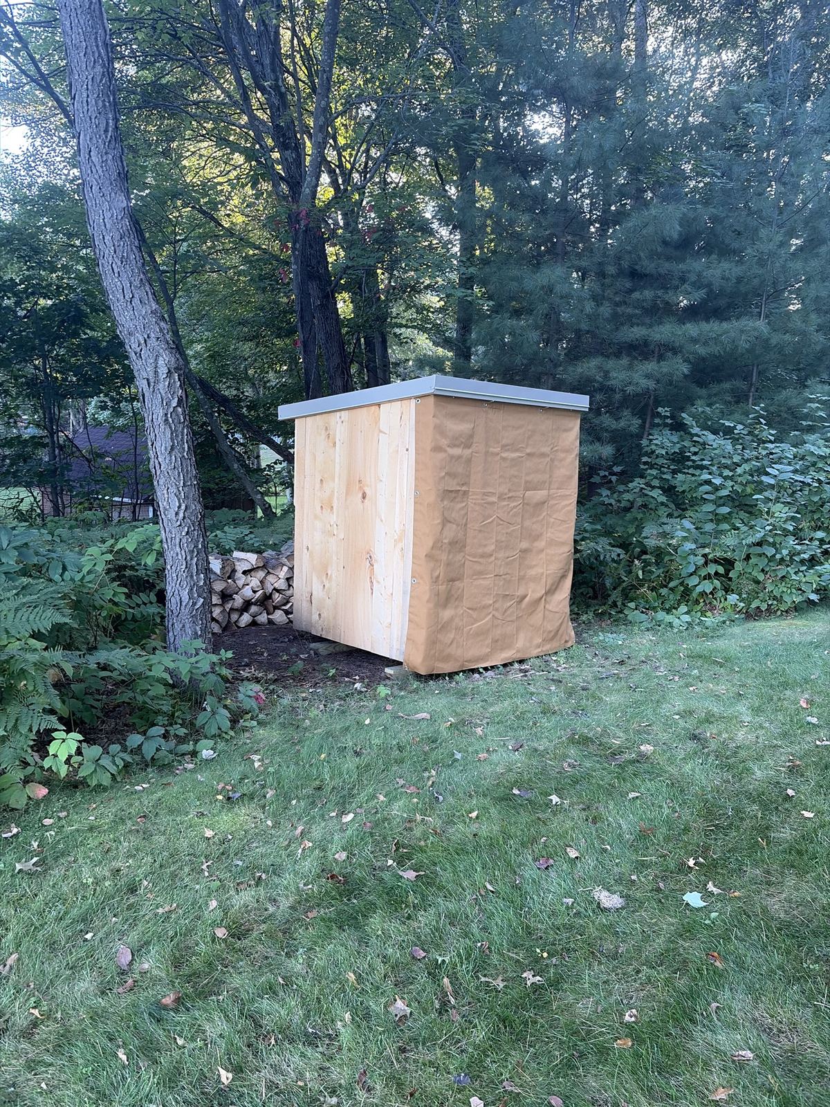 Wood shed in a backyard with a tan canvas cover over the front